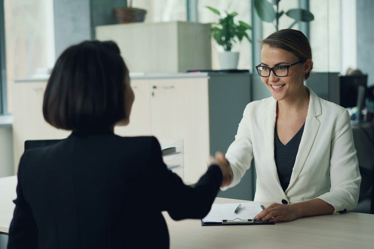 Two people shaking hands across a desk